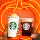Hands toasting Starbucks Pumpkin Spice Latte and Pumpkin Cream Cold Brew in front of pumpkin neon sign